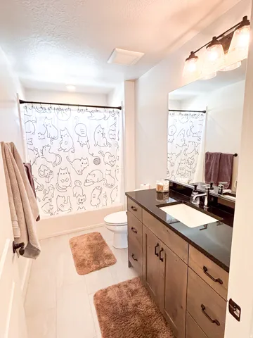 Wood-finish vanity with a black countertop and an integrated rectangular sink