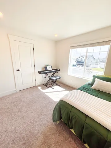 Recessed lighting, light-toned carpeting, white interior door with dark hardware, large window with blinds, and white trim throughout