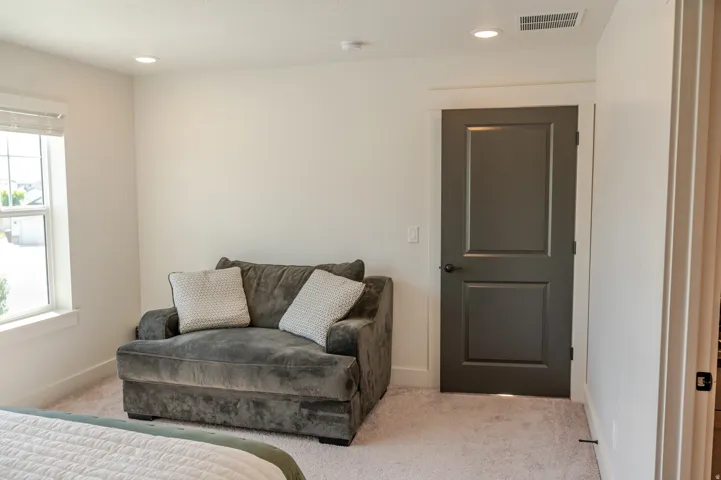 Recessed lighting, light-toned carpeting, white window trim, and a paneled interior door with dark hardware