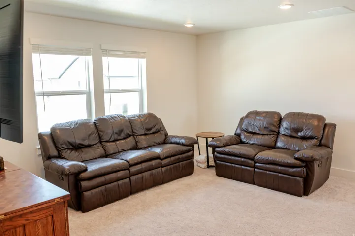 Neutral-toned carpeting, recessed ceiling lighting, and two windows with blinds