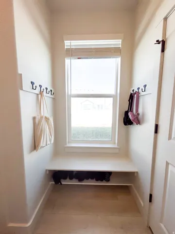 Built-in bench seating with shoe storage, complete with wall-mounted coat hooks and a single window