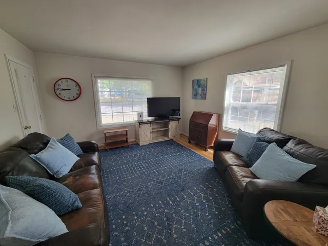 Laminate Flooring with area rug, and blinds on the windows