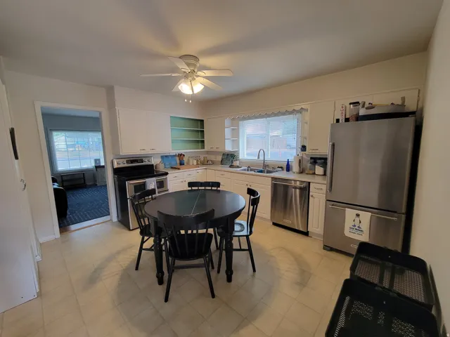 Kitchen with a ceiling fan, white cabinetry, stainless steel appliances, and a window above the sink