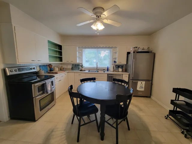 Kitchen featuring white cabinetry, light-toned flooring, stainless steel appliances, and a ceiling fan