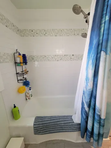 White subway tile shower surround with decorative mosaic tile accent