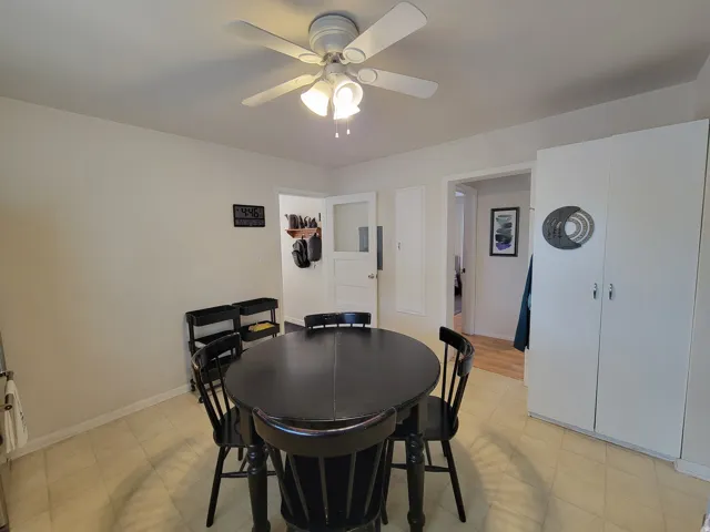 Recessed panel cabinetry, overhead ceiling fan with lighting, and light-toned tile flooring
