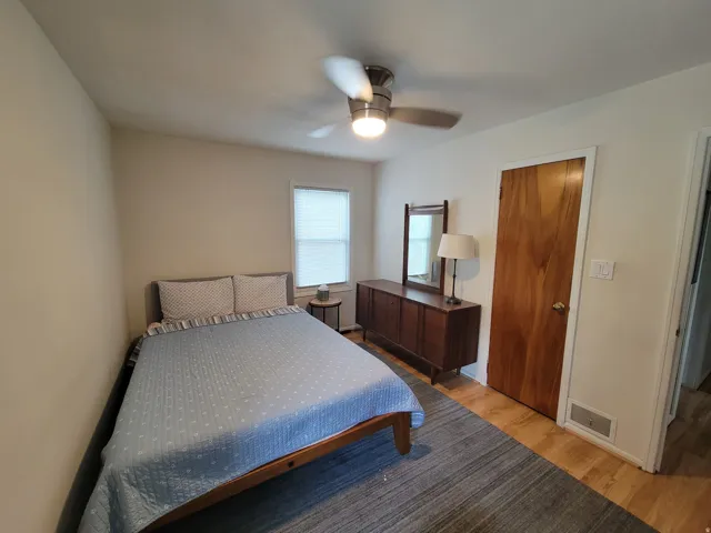 Wood-finish flooring, light neutral wall color, and a ceiling fan with integrated lighting