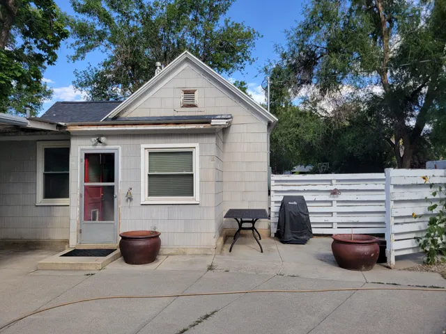 Exterior with light gray shingle siding, a dark gray shingle roof, and a white wood fence