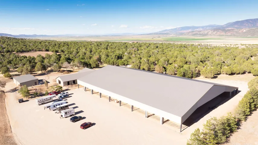 Expansive property featuring multiple large outbuildings, extensive unpaved parking, and a prominent covered equestrian arena