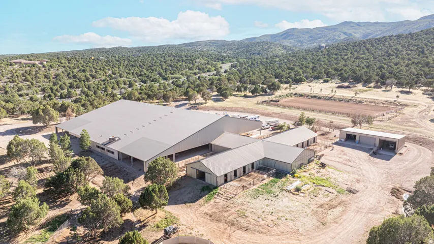 Expansive property featuring multiple large metal-roofed structures, a substantial arena, and additional outbuildings