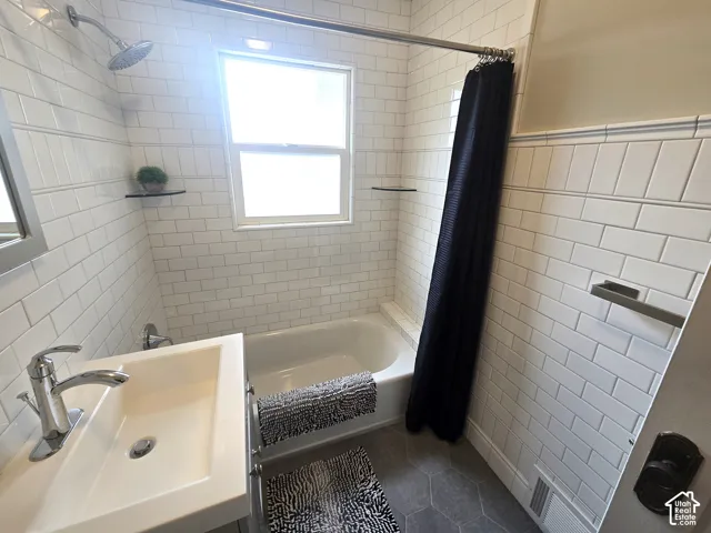 Bathtub with subway tile surround, hexagonal floor tiling, and a vanity with an integrated sink