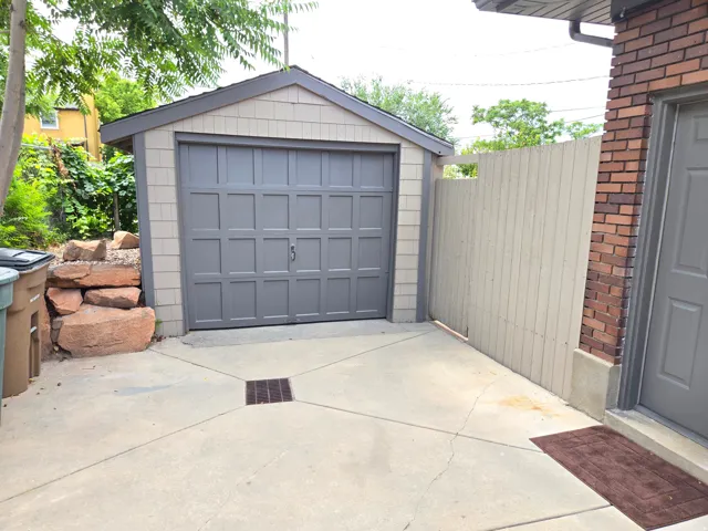 Detached garage with a paneled door, horizontal siding, and a shingled roof