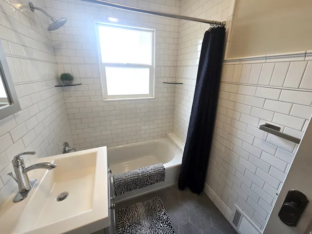 Bathtub with subway tile surround, hexagonal floor tiling, and a vanity with an integrated sink