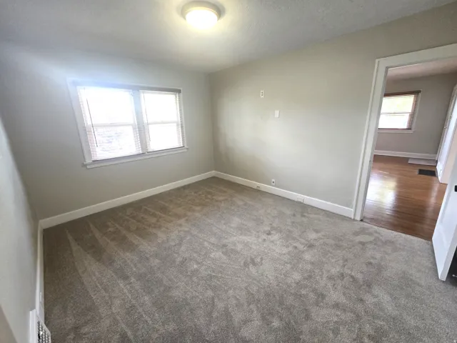Bright corner bedroom with dual windows providing natural light, neutral wall finishes, and soft-toned carpeting throughout