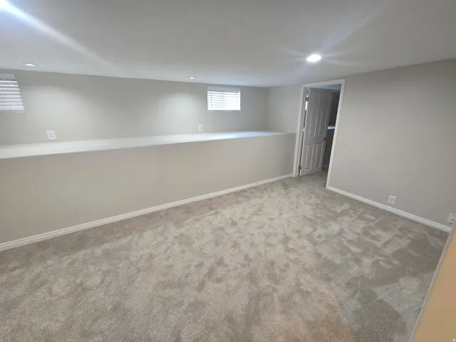 Recessed lighting, light-toned walls, two windows with blinds, light gray carpet, and white trim