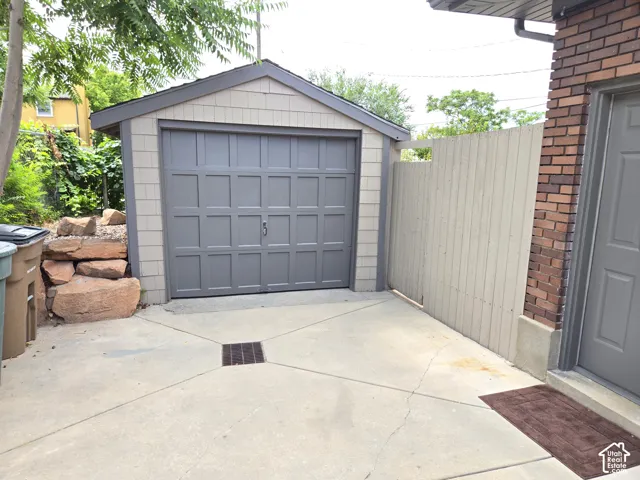 Detached garage with a paneled door, horizontal siding, and a shingled roof