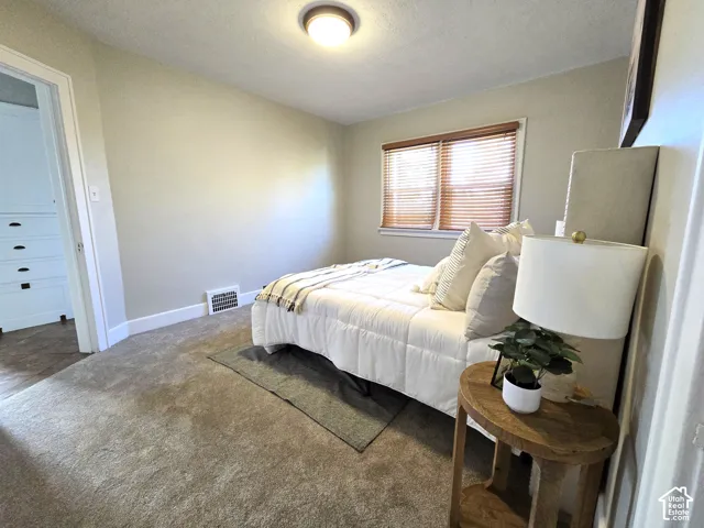 Neutral-toned interior featuring wall-to-wall carpeting, recessed ceiling lighting, and window blinds with a natural finish