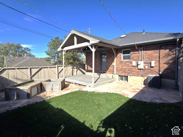 Brick exterior with a covered patio, flagstone hardscaping, custom raised garden beds, and wood privacy fencing