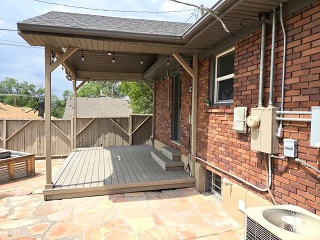 Covered patio featuring composite decking, a shingled roof, and string lighting