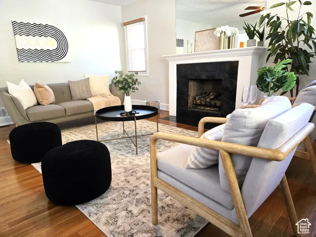 Fireplace with a black stone surround and white mantel, wood-finish flooring, and large wall mirror