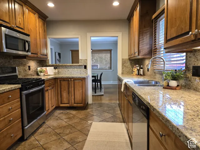 Kitchen featuring stained wood cabinetry, stone-surface countertops, tile flooring, recessed lighting, and stainless steel appliances