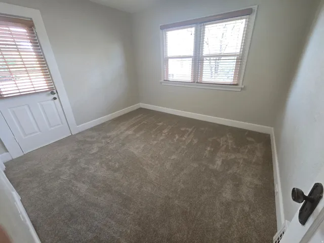 Neutral wall color, wall-to-wall carpeting, and natural light from a window with blinds