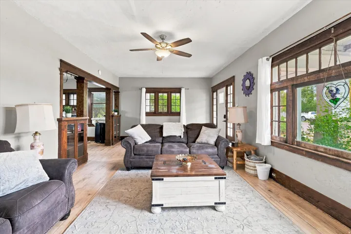 Hardwood-finish flooring, exposed wood trim, ceiling fan light fixture, and arched doorway