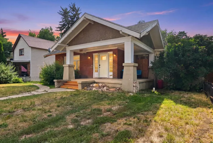 Brick exterior, covered front porch, concrete porch foundation, wooden porch steps, and white-framed front door