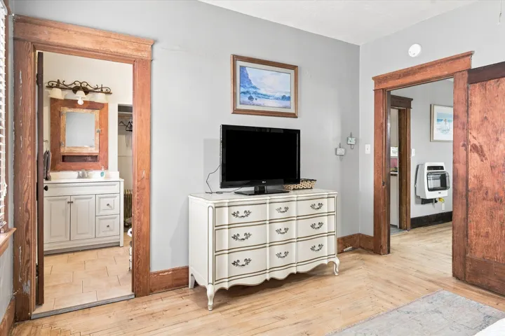 Hardwood flooring, light gray wall paint, and exposed wood trim around doorways