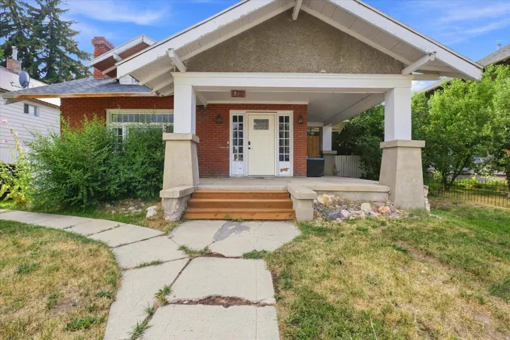 Brick exterior with a covered porch, wood stairs, and concrete pathway