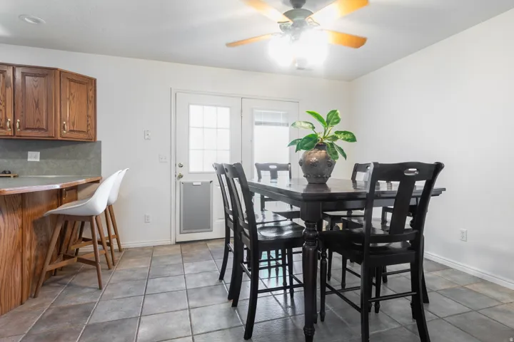 Warm wood-finish cabinetry, tile flooring, ceiling fan, and a double glass-panel door
