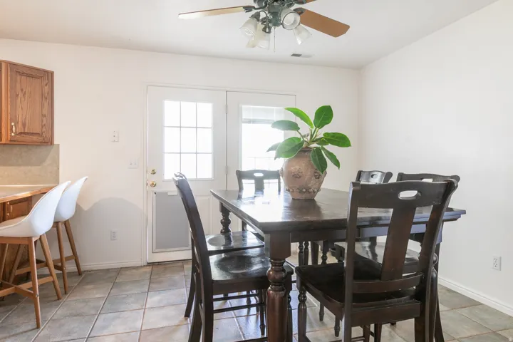 Tile flooring, wood cabinetry, built-in breakfast bar, ceiling fan, and French doors