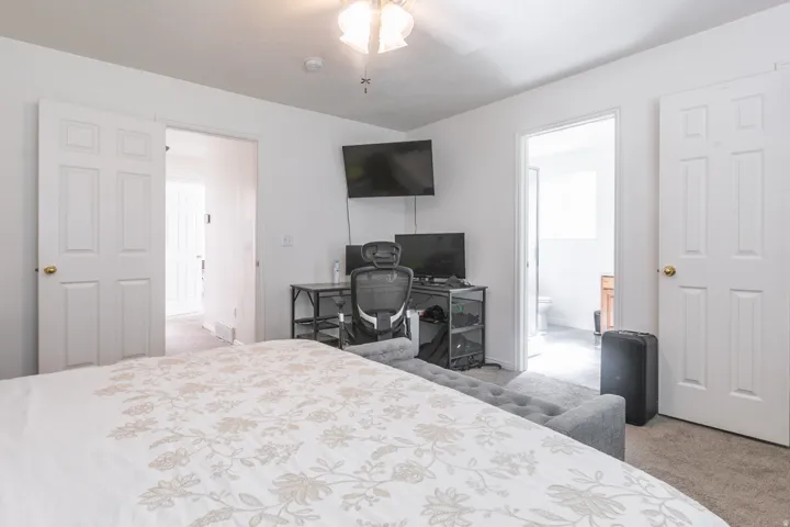 Carpeted room with a ceiling fan and a white paneled door
