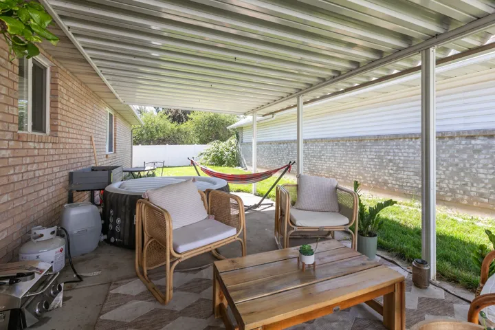 Covered patio featuring a metal roof, concrete flooring, and brick exterior