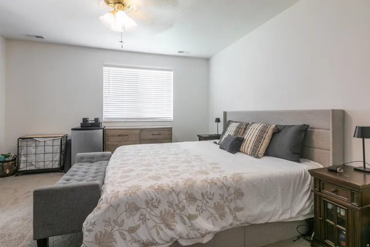 Spacious room with a ceiling fan, carpet flooring, and a large window with blinds