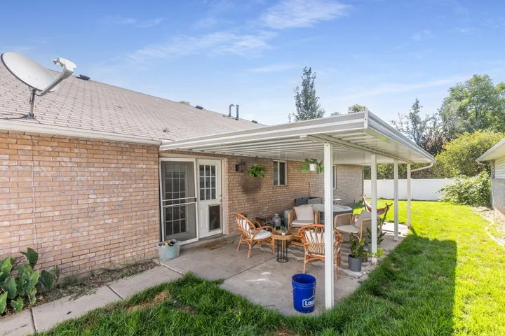 Brick exterior with a covered patio, concrete patio surface, and a sliding glass door