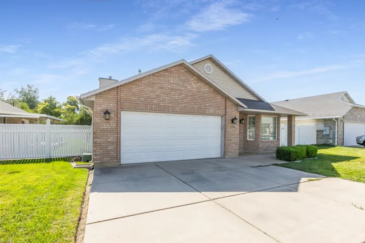 Brick exterior with light-colored siding accents, attached two-car garage, concrete driveway, and front lawn