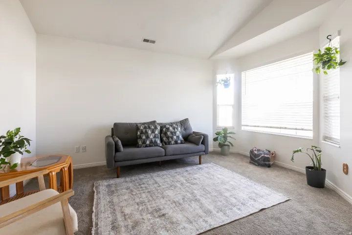 Vaulted ceiling, multiple windows, wall-to-wall carpeting, and neutral wall tones