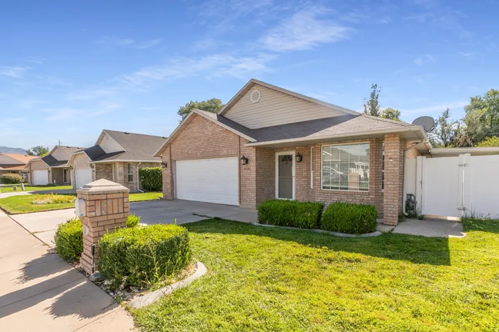 Brick exterior with siding accents, attached garage, front yard landscaping, and white privacy fence