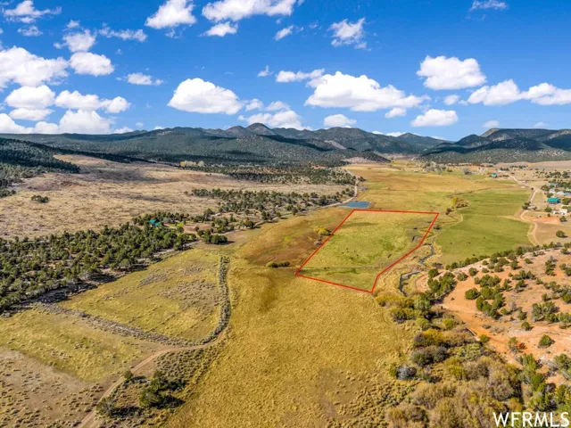 Expansive land parcel featuring open fields, a natural waterway, and a distant mountain range