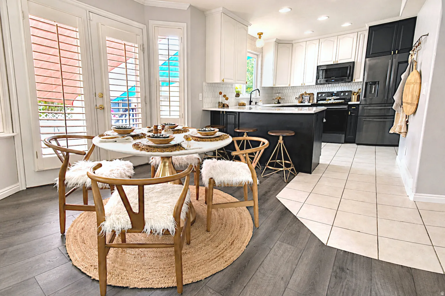 Kitchen featuring a two-tone cabinetry design, black appliances, bar seating, and wood-finish flooring