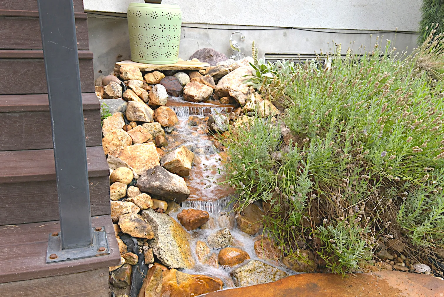 Water feature with natural stone, composite decking, and established plantings