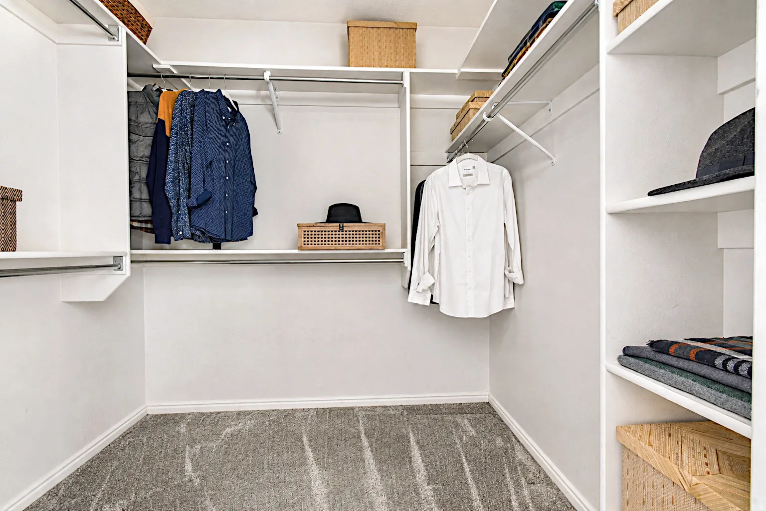 Walk-in closet with white shelving, multiple hanging rods, and built-in shelving units