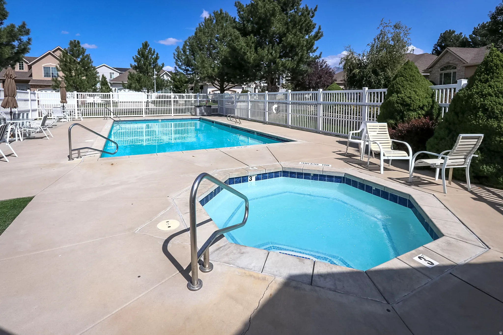 Outdoor swimming pool with integrated spa and surrounding concrete decking