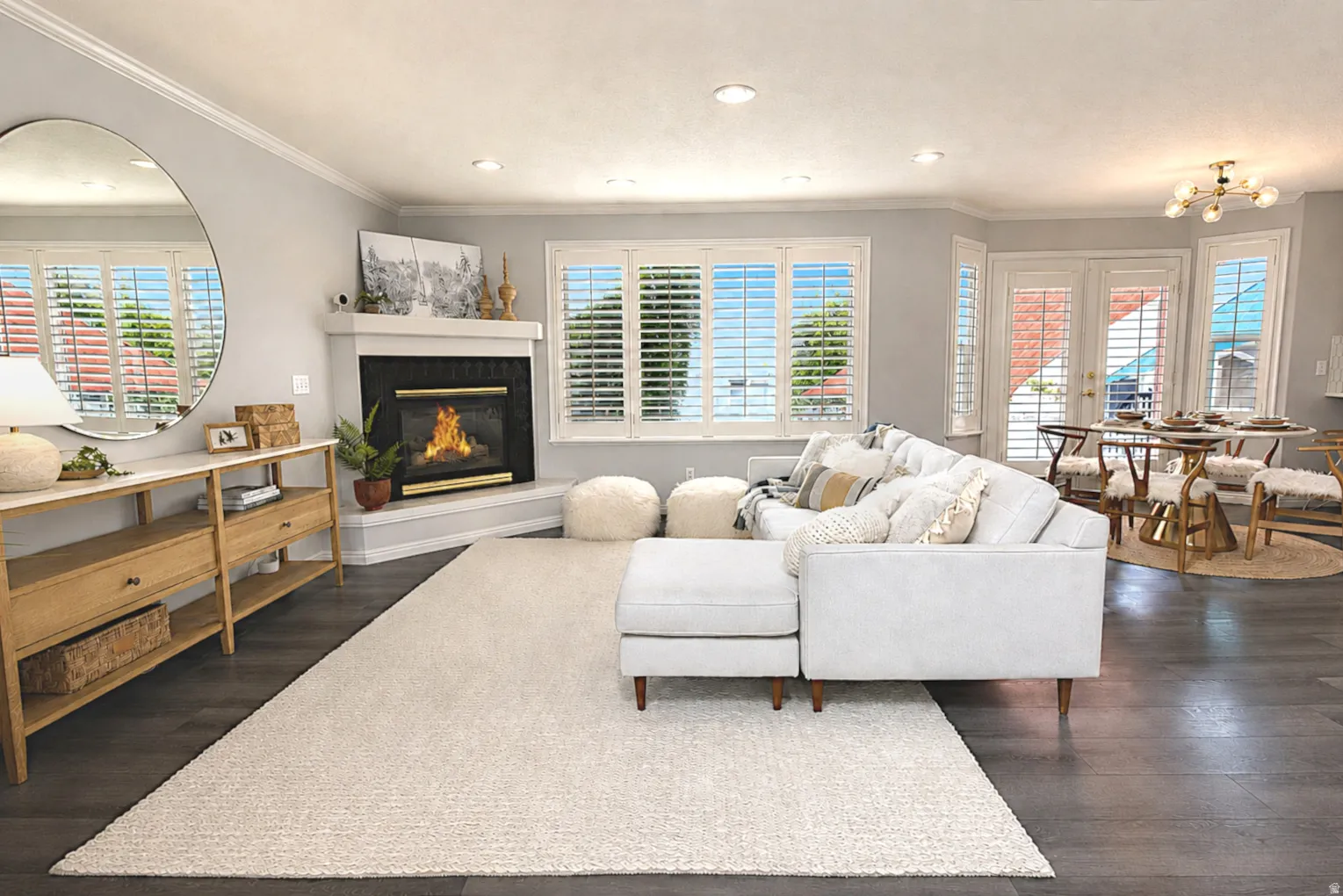Living space featuring wood-finish flooring, a fireplace with a mantel, crown molding, and plantation shutters