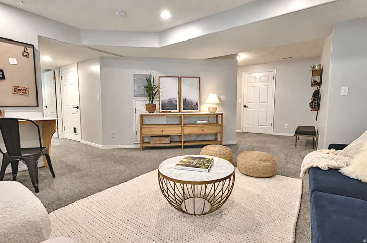 Carpeted living area with recessed lighting, and white paneled doors,