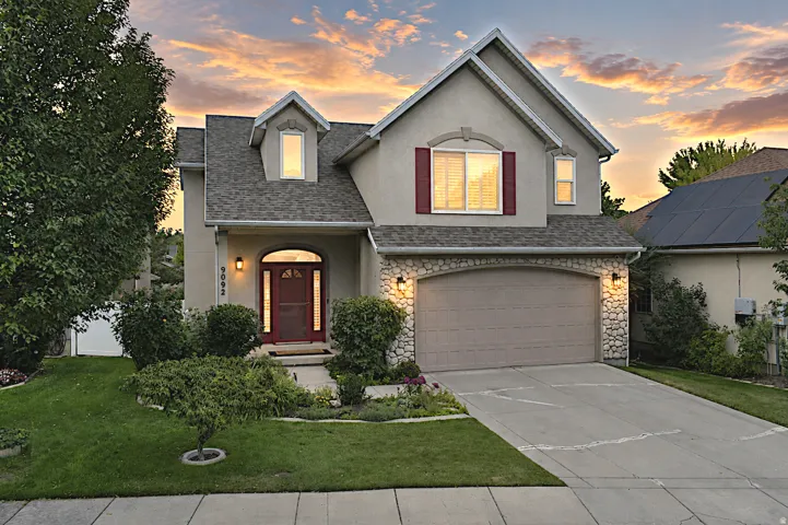 Stucco exterior with stone accents, an arched entry, a two-car garage, and a dormer window