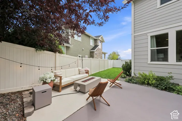Private outdoor patio with a concrete surface, bordered by a white privacy fence and a manicured lawn