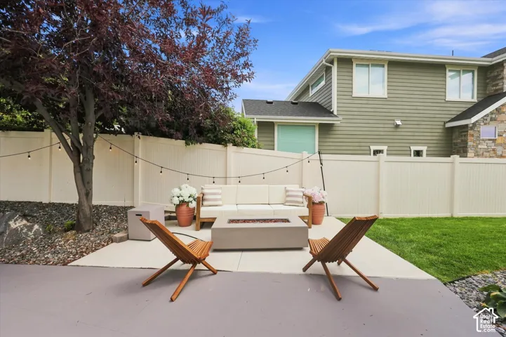 Private backyard with a concrete patio, fire pit, and level lawn