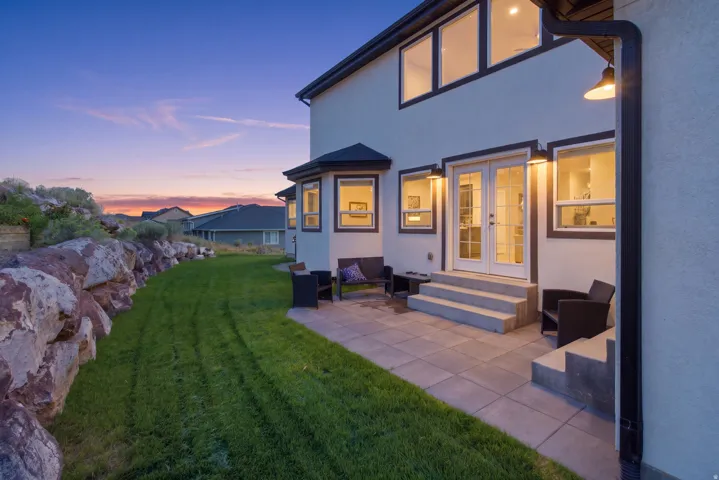Expansive patio with stone pavers, French doors, and exterior wall lighting